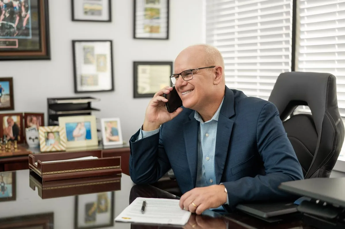 Dave Petkovsek at his desk in Palm Coast, smiling while on a phone call